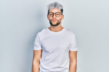 Modern boyalı saçlı, beyaz tişörtlü ve gözlüklü, havaya öpücük yollayan genç İspanyol bir adam. Güzel ve seksi. aşk ifadesi. 