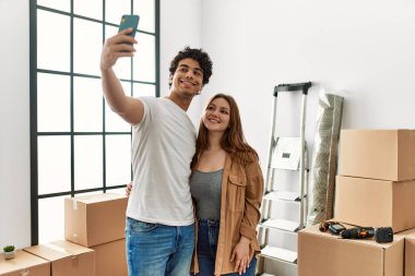 Young couple smiling happy making selfie by the smartphone at new home.