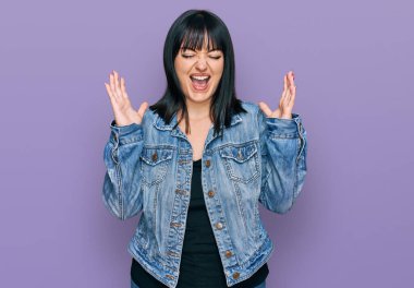 Gündelik kıyafetler giyen genç İspanyol kadın başarı için deli ve çılgınlığı kutluyor kollarını kaldırmış ve gözlerini kapatmış heyecanla bağırıyor. Kazanan konsept 