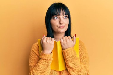 Genç İspanyol kadın elinde kitapla gülümseyip yan tarafa bakıyor ve düşünüyor.. 