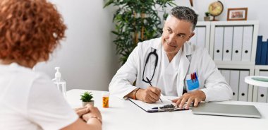 Doktor üniforması giyen orta yaşlı bir adam ve kadın klinikte tıbbi danışmanlık yapıyorlar.