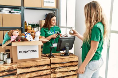 İki gönüllü kadın, hayır kurumunda çalışmaktan mutlu gülümsüyor..