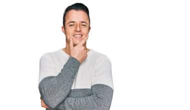Kış süveteri giyen yakışıklı genç adam kameraya kendinden emin bakıyor kollarını kavuşturmuş ve çenesini kaldırmış gülümsüyor. Olumlu düşünmek. 