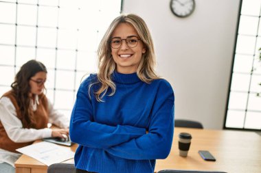 İş kadını kollarını kavuşturup mutlu bir şekilde gülümsüyor..