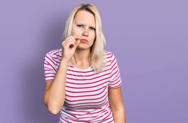 Gündelik kıyafetler giyen genç beyaz kadın ağzı ve dudakları parmaklarıyla fermuar gibi kapalı. gizli ve sessiz, tabu konuşması 