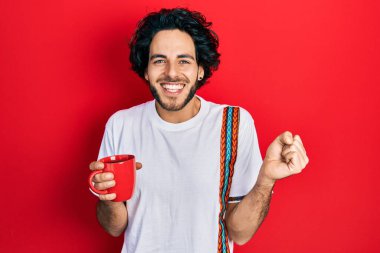 Yakışıklı İspanyol adam bir fincan kahve içiyor gururla bağırıyor, zaferi kutluyor ve başarıyı kollarını kaldırarak kutluyor. 