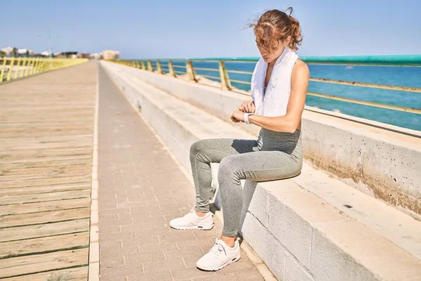 年轻的高加索女人穿着运动服 看着海边的手表 — 图库照片
