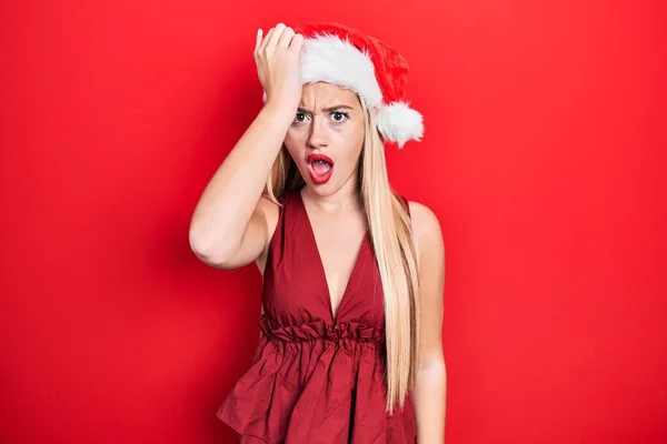 Chica Rubia Joven Con Sombrero Navidad Sorprendido Con Mano Cabeza — Foto de Stock