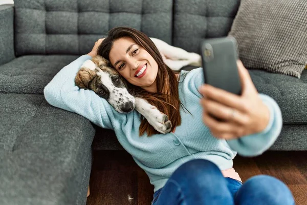 年轻的女人抱着狗 在家用智能手机自拍 — 图库照片