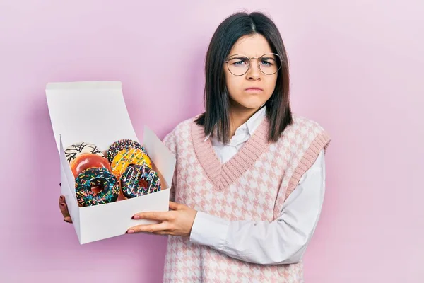 Mulher Morena Jovem Segurando Saborosos Donuts Coloridos Cético Nervoso Franzindo — Fotografia de Stock