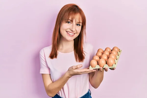 Rudowłosa Młoda Kobieta Pokazuje Świeże Jaja Patrząc Pozytywnie Szczęśliwy Stojąc — Zdjęcie stockowe