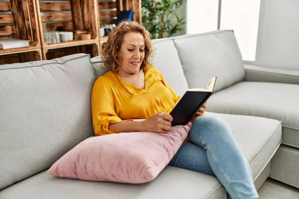 Orta Yaşlı Beyaz Kadın Kitap Okuyor Evdeki Kanepede Oturuyor — Stok fotoğraf