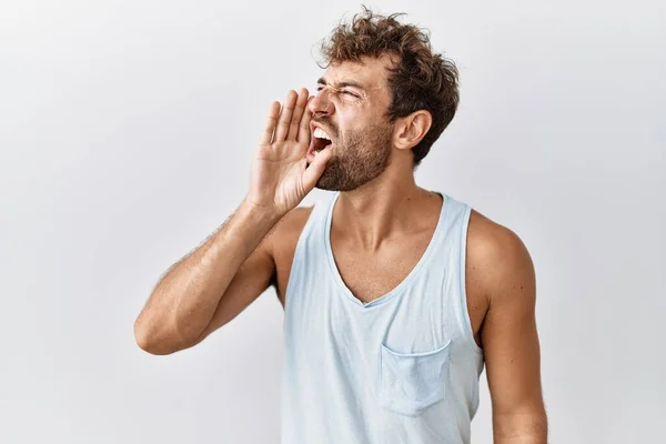 孤立した背景の上に立つ若いハンサムな男は大声で叫び 口の上に手で横に大声で叫ぶ コミュニケーションの概念 — ストック写真