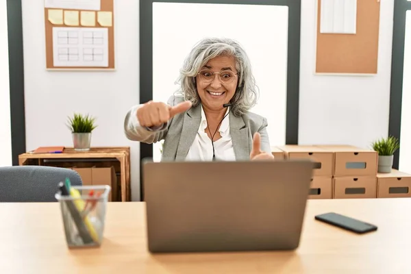 中年女商人坐在办公桌前工作 在办公室里使用笔记本电脑 赞许她用手做积极的手势 微笑着竖起大拇指 为成功感到高兴 优胜手势 — 图库照片