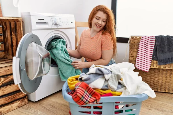 洗濯室で洗濯機を使って若い赤毛の女性のクリーニング服 — ストック写真