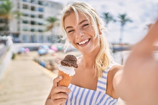 年轻的金发女孩在海滩边的相机边吃着自己做的冰淇淋 — 图库照片