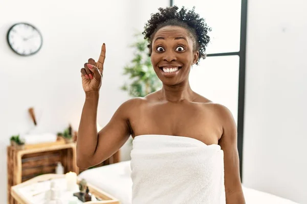 若いアフリカ系アメリカ人の女性は 美容センターにタオルを着用し 成功したアイデアで指を指しています 興奮して幸せよ 第1位 — ストック写真