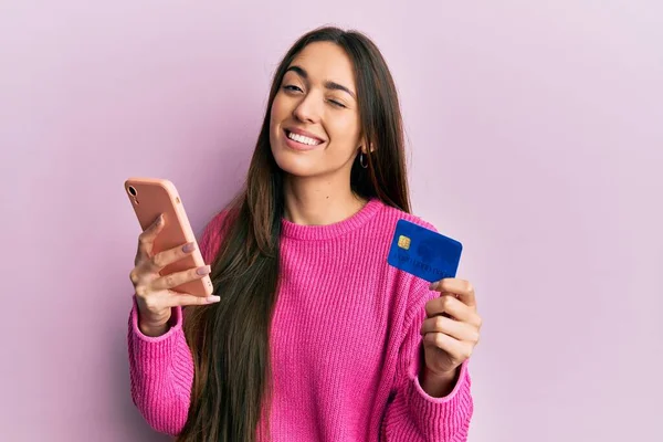 Junges Hispanisches Mädchen Mit Smartphone Und Kreditkarte Zwinkernd Die Kamera — Stockfoto