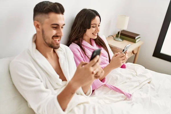 Jong Hispanic Paar Met Behulp Van Smartphone Liggend Bed Thuis — Stockfoto