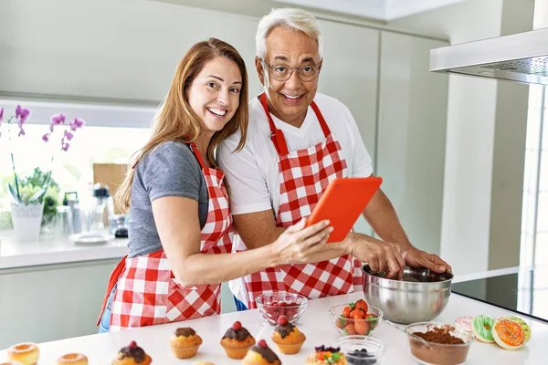 Casal Hispânico Meia Idade Sorrindo Feliz Usando Touchpad Cozinhar Muffins — Fotografia de Stock