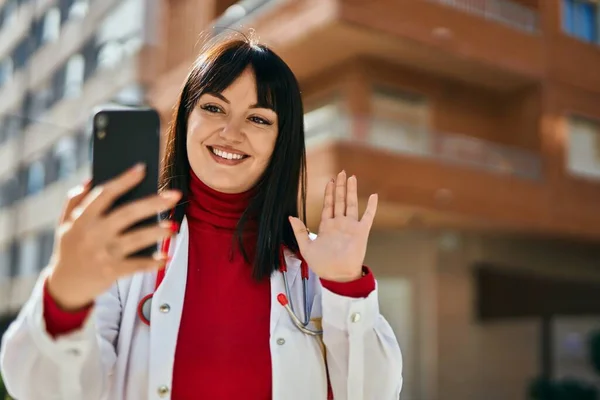 年轻的黑发女人穿着医生制服 在城里用智能手机进行视频拍摄 — 图库照片