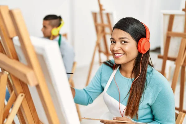 若いラテン画家のカップル笑顔幸せな絵とアートスタジオでヘッドフォンを使用して — ストック写真