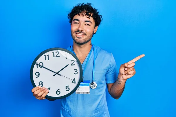 Jeune Homme Hispanique Portant Bleu Infirmière Uniforme Tenant Horloge Souriant — Photo