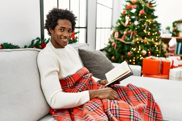 Joven Hombre Afroamericano Leyendo Libro Sentado Sofá Por Árbol Navidad —  Fotos de Stock