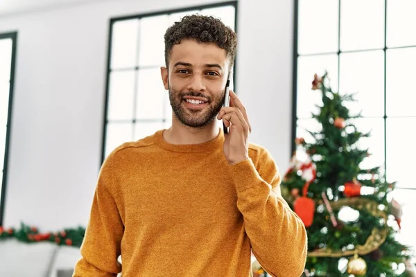 Young Arab Man Talking Smartphone Standing Christmas Tree Home — Stock Photo, Image