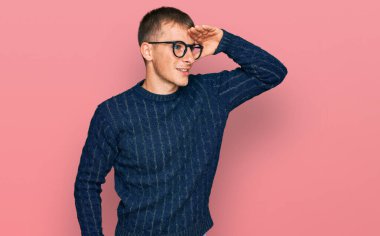 Gündelik kıyafetler ve gözlük takan genç sarışın adam çok mutlu ve gülümseyerek başını kaldırmış uzaklara bakıyor. arama kavramı. 