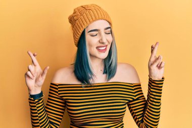 Yün şapka takan genç modern kız umut ve gözlerin kapalı gülümseyerek el sallıyor. Şans ve batıl inançlar. 