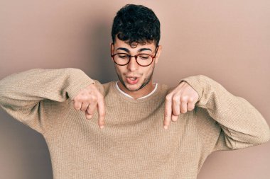 Gündelik kıyafetler giyen ve gözlük takan genç İspanyol reklamını gösteren parmaklarıyla işaret ediyor, şaşırmış bir yüz ve açık bir ağız. 