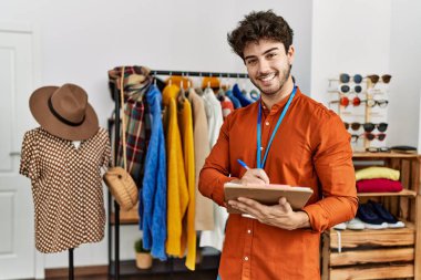 Genç İspanyol esnaf gülümsüyor. Giyim mağazasında çalışan panoya mutlu yazılar yazıyor..