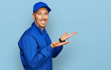 Sakallı, inşaatçı tulumu giymiş kel bir adam. Avuç içleri açık, fotokopi alanını gösteriyor. Gülümseyen mutlu bir gülümseme var. 