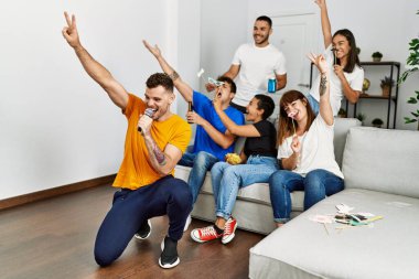 Bir grup genç arkadaş evde mikrofon kullanarak şarkı söylüyor..