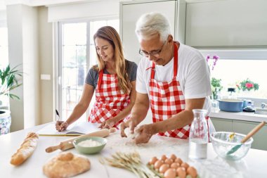 Orta yaşlı İspanyol çift gülümseyerek mutfakta mutlu ekmek pişiriyor..