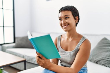 Genç İspanyol kadın evde kendinden emin bir şekilde kitap okuyordu.