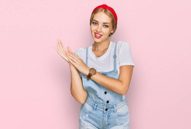 Kafkasyalı genç bir kız günlük giysiler içinde alkışlıyor ve mutlu ve neşeli alkışlıyor, gururla gülümsüyor. 