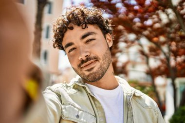 Yakışıklı, sakallı, güneşli bir günde mutlu bir şekilde gülümseyen ve selfie çeken bir İspanyol.