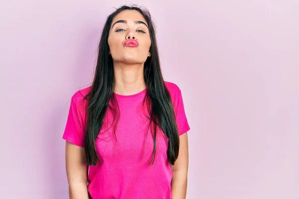Joven Chica Hispana Vistiendo Casual Camiseta Rosa Mirando Cámara Soplando —  Fotos de Stock