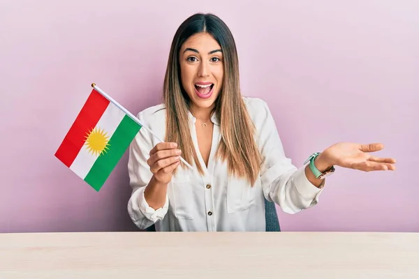 Fiatal Spanyol Kezében Kurdisztán Zászló Asztalon Ünneplő Teljesítmény Boldog Mosollyal — Stock Fotó