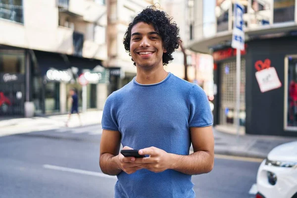 Nuori Latino Mies Hymyilee Luottavainen Käyttämällä Älypuhelin Kadulla — kuvapankkivalokuva
