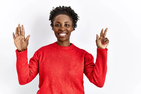 自信を持って幸せな笑顔ながら 孤立した背景の上にカジュアルな服を身に着けている若いアフリカ系アメリカ人の女性は 指の数8を示すと指摘 — ストック写真