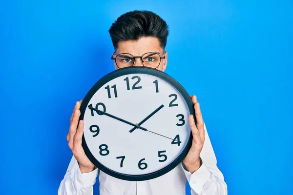 Giovane Uomo Ispanico Tenendo Grande Orologio Sul Viso Faccia Shock — Foto Stock