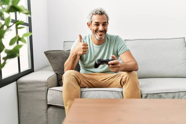 Hombre Hispano Mediana Edad Jugando Videojuego Sentado Sofá Sonriendo Feliz —  Fotos de Stock