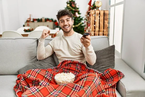 Young Hispanic Man Eating Popcorn Sitting Sofa Christmas Tree Screaming — Stock Fotó