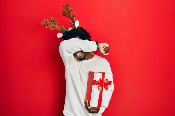 Young African American Man Wearing Deer Christmas Hat Holding Gift — Fotografia de Stock