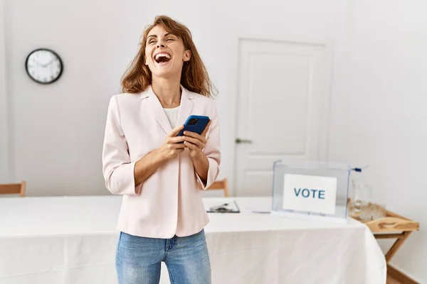 若い白人有権者の女性が選挙大学でスマートフォンを使って笑顔で幸せ — ストック写真