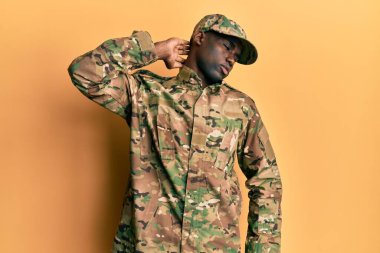 Asker üniforması giyen, boynu ağrıyan, eli boynuna dokunan, kas ağrısı çeken genç bir Afro-Amerikan. 