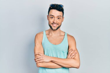 Yaz stili gülen yüz takınan genç İspanyol adam kollarını kavuşturup kameraya bakıyor. pozitif kişi. 